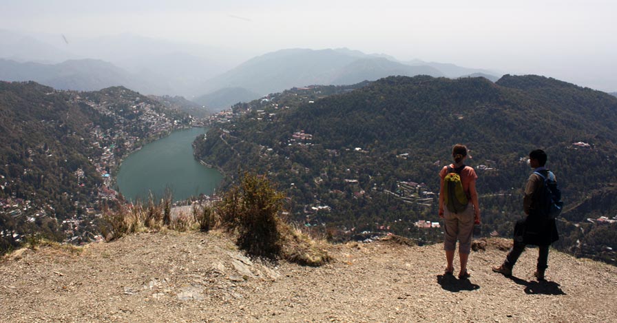 a scenic overlook of nainital with mountains, forest, and a lake